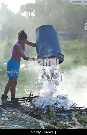 Giovane donna di gettare rifiuti in plastica su un sito per lo smaltimento dei rifiuti nei pressi di baraccopoli (favela) Imbiribeira, Recife, Brasile Foto Stock
