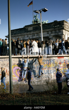 Caduta del muro di Berlino: persone da Berlino Ovest e Berlino Est salendo sulla parete presso la Porta di Brandeburgo, Berlino, Germania Foto Stock