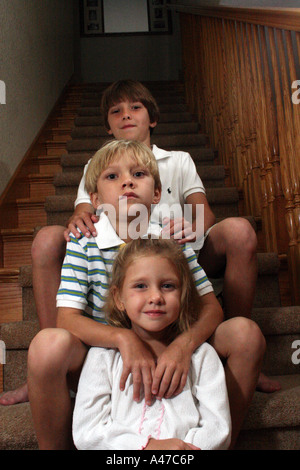 Tre bambini seduti su una scala Foto Stock
