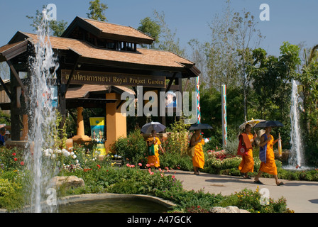 I monaci buddisti portano ombrelloni e camminare sotto il padiglione nel giardino con due fontane di spruzzatura in Chiang Mai Thailandia Foto Stock