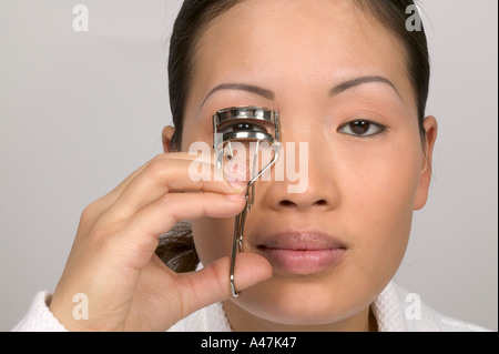 Donna che utilizza un bigodino di ciglia Foto Stock