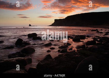 Vista verso il nero al NAB Saltwick Bay nei pressi di Whitby nel Nord Yorkshire coast mostra nuvole turbolento rosso incandescente al crepuscolo Foto Stock