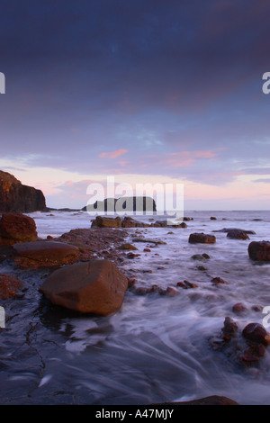 Luce rossa all'alba le catture di massi e scogliere guardando verso Saltwick Nab a Saltwick Bay nei pressi di Whitby sulla costa dello Yorkshire Foto Stock