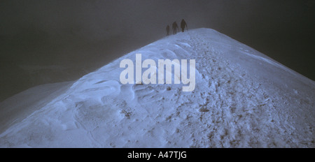 Un team di tre scalatori in minaccioso meteo sulla vetta del Breithorn nelle Alpi Svizzere Foto Stock