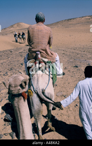 I turisti provenienti da una nave da crociera a dorso di cammello nel deserto vicino al monastero di San Simeone Egitto Foto Stock