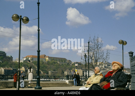 Le persone che si godono il sole primaverile sulle rive del Danubio a Budapest Ungheria Foto Stock