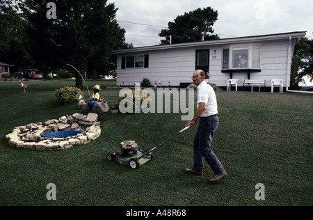 Lincoln Highway. l uomo falciare il giardino prato di fronte al bungalow lala motte luxembourgian un insediamento in prossimità di Clinton iwowa 1993 Foto Stock