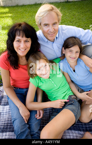Famiglia seduta nel prato, sorridente, ritratto Foto Stock