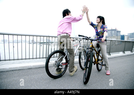 Due giovani uomini seduti su una bicicletta e dando alta cinque Foto Stock