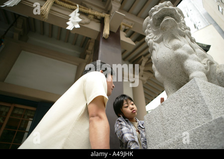 Basso angolo vista di una metà uomo adulto e suo figlio in piedi accanto a una statua di un leone Foto Stock