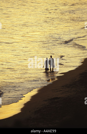 Giovane camminando lungo il litorale a bordo delle acque al tramonto California USA Foto Stock