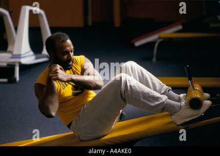 L'uomo facendo sit ups su una scheda di inclinazione in corrispondenza di un centro sportivo a Hackney Foto Stock