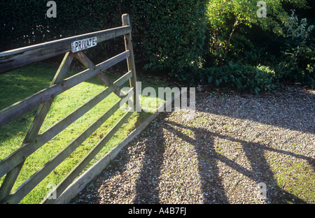 Sette di legno bar porta cuscinetto un avviso privato aperto in piedi accanto a prato e la colata di lunga ombra autunnali attraverso unità di ghiaia Foto Stock