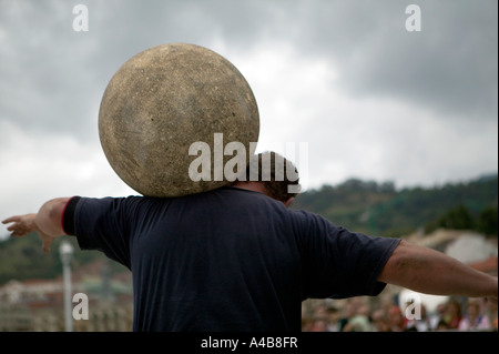 Harrijasotzaileak (pietra sollevamento) concorrente portando la sfera di granito su spalle, basco uomo forte giochi, Bilbao, Paese Basco Foto Stock