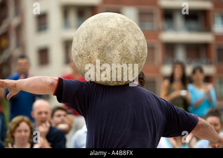 Harrijasotzaileak (pietra sollevamento) concorrente portando la sfera di granito su spalle, basco uomo forte giochi, Bilbao, Paese Basco Foto Stock