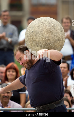 Harrijasotzaileak (pietra sollevamento) concorrente portando la sfera di granito su spalle, basco uomo forte giochi, Bilbao, Paese Basco Foto Stock