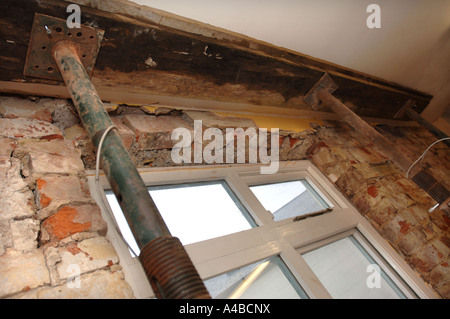 Puntelli ACROW tenendo un soffitto e travetti al fine di rimuovere una vecchia finestra con architravi inadeguata Foto Stock