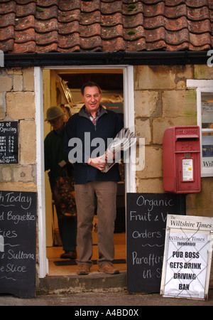 Il Postmaster presso un negozio del villaggio e ufficio postale a MONKTON FARLEIGH WILTSHIRE REGNO UNITO CHE È SOTTO LA MINACCIA DI CHIUSURA Dic 2006 Foto Stock