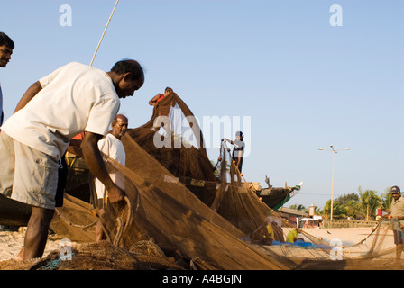 Immagine di stock di Goa pescatori caricamento di reti da pesca su barche da pesca sulla spiaggia Benaulim in Goa in India Foto Stock