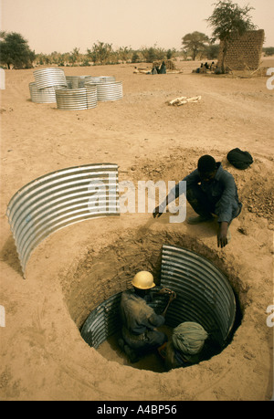 Operai scavare un pozzo nuovo, pagato da una ONG, rivestiti di ferro coriggated per una siccità che ha colpito il villaggio Agelock, Mali Foto Stock