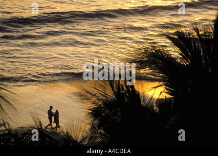 Giovane camminando lungo la spiaggia al tramonto con palme Zihuatanejo Messico Foto Stock