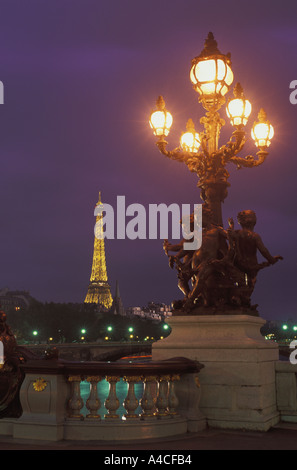 Luci oltre statua barocca sul Pont Alexandre III con la Torre Eiffel Foto Stock