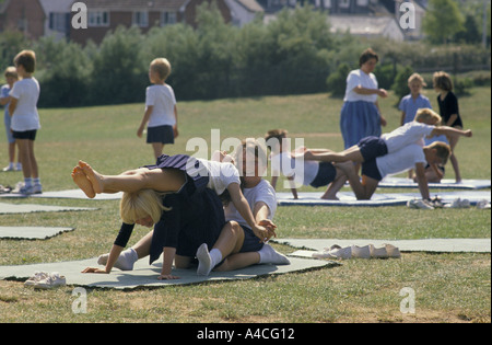 Gli alunni facendo esercizio sul tappetino durante l'EDUCAZIONE FISICA lezione nella scuola primaria Foto Stock