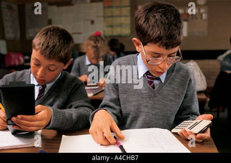 Ragazzi e ragazze in un misto di completo scuola utilizzare calcolatori durante una classe di matematica Foto Stock