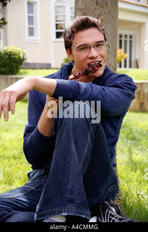 L'uomo mangiare souvlaki al barbecue Foto Stock