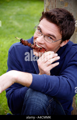 L'uomo mangiare souvlaki al barbecue Foto Stock