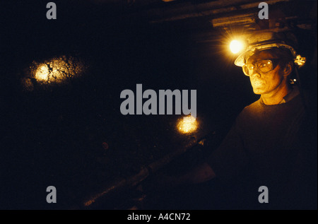 COALMINERS con torcia da testa & casco, cammina nel buio nel tunnel sotterraneo. Foto Stock