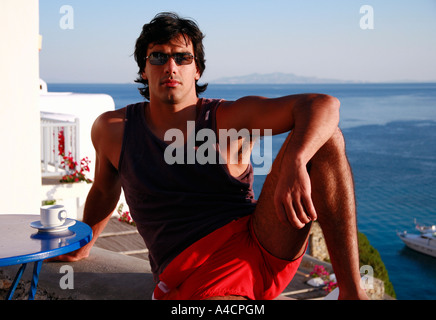 Giovane uomo seduto sul balcone con vista Foto Stock