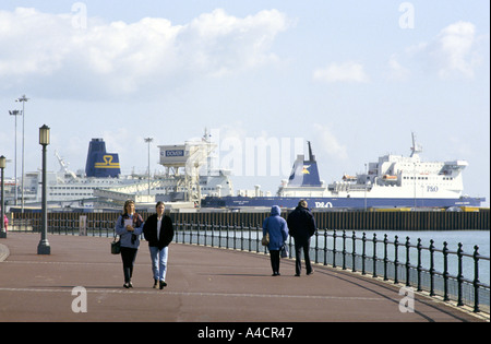La gente a piedi lungo la passeggiata a Dover in Inghilterra del sud est della costa con le navi nella città di porto di traghetti in background Foto Stock