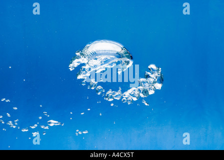 Una grande e luminosa bolla d'aria e un sacco di piccoli prima di sfondo blu in aumento di superficie di acqua Foto Stock