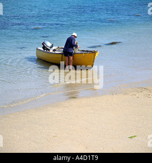 Un uomo e la sua barca sull'isola di Bryher nelle isole Scilly western England Regno Unito Regno Unito Foto Stock