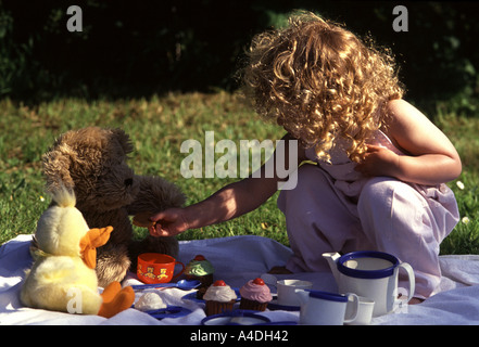 Bambina avente un Teddy bear's picnic nel giardino Foto Stock