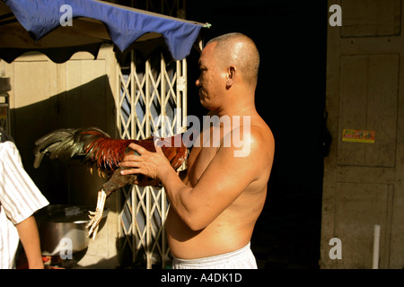 Un uomo con un gallo presso il mercato del pollame. A Saigon, Vietnam Foto Stock