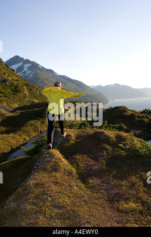 Alaska donna escursionismo su terreno alpino al di sopra di Prince William Sound vicino a portage passare su una chiara mattina di sole Foto Stock