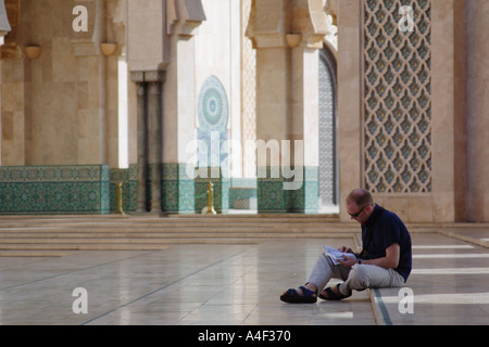 Maschio caucasico leggendo la guida in moschea di Hassan II Casablanca Marocco Foto Stock