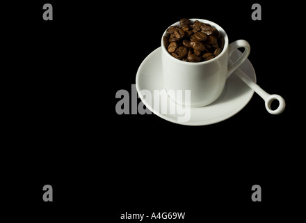 White tazzina e piattino contenente i chicchi di caffè isolato su sfondo nero con tracciato di ritaglio Foto Stock