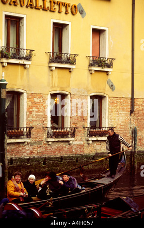 Luce calda del pomeriggio gondoliere in piedi sul retro della gondola di prendere i turisti in tutta calma canali Venezia Italia Europa Foto Stock