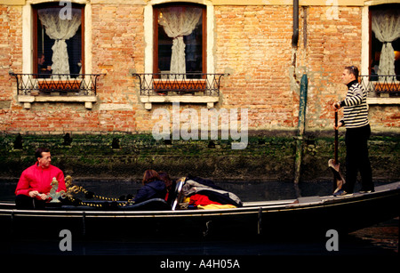 Luce calda del pomeriggio gondoliere in piedi sul retro della gondola di prendere i turisti in tutta calma canali Venezia Italia Europa Foto Stock