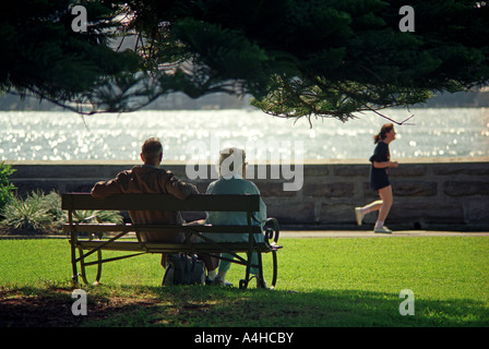 Jogging, una coppia di anziani guarda un giovane del jogging nel parco, Sydney, Australia Foto Stock
