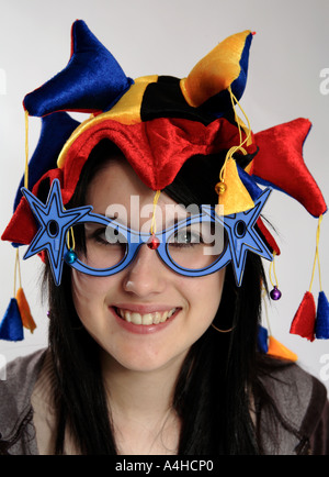 Ragazza giovane di 15 anni con un giullari cappello e occhiali novità sorridente Foto Stock