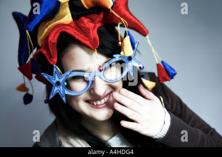 Giovane donna con giullari cappello e occhiali novità ridere Foto Stock