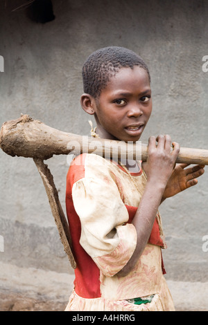 Una giovane ragazza che porta una vanga pesante o Khasu (HOE) nel villaggio di Mambala Africa Malawi Foto Stock