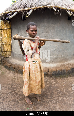 Una giovane ragazza che porta una vanga pesante o Khasu (HOE) nel villaggio di Mambala Africa Malawi Foto Stock