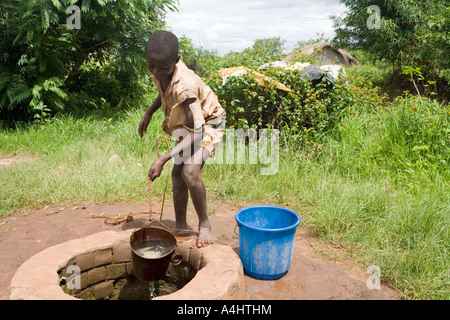 Ragazzo il prelievo di acqua da un pozzo nel villaggio di Mambala, Malawi, Africa Foto Stock