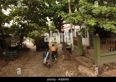 Due persone in sella bici su una strada nel villaggio vicino fiume Irrawaddy MYANMAR Birmania Foto Stock