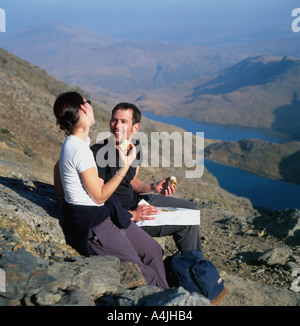 Gli escursionisti di mangiare le mele di prendere un periodo di riposo e guardando una mappa mentre si cammina fino a Mount Snowdon nella primavera del Parco Nazionale di Snowdonia Wales UK KATHY DEWITT Foto Stock